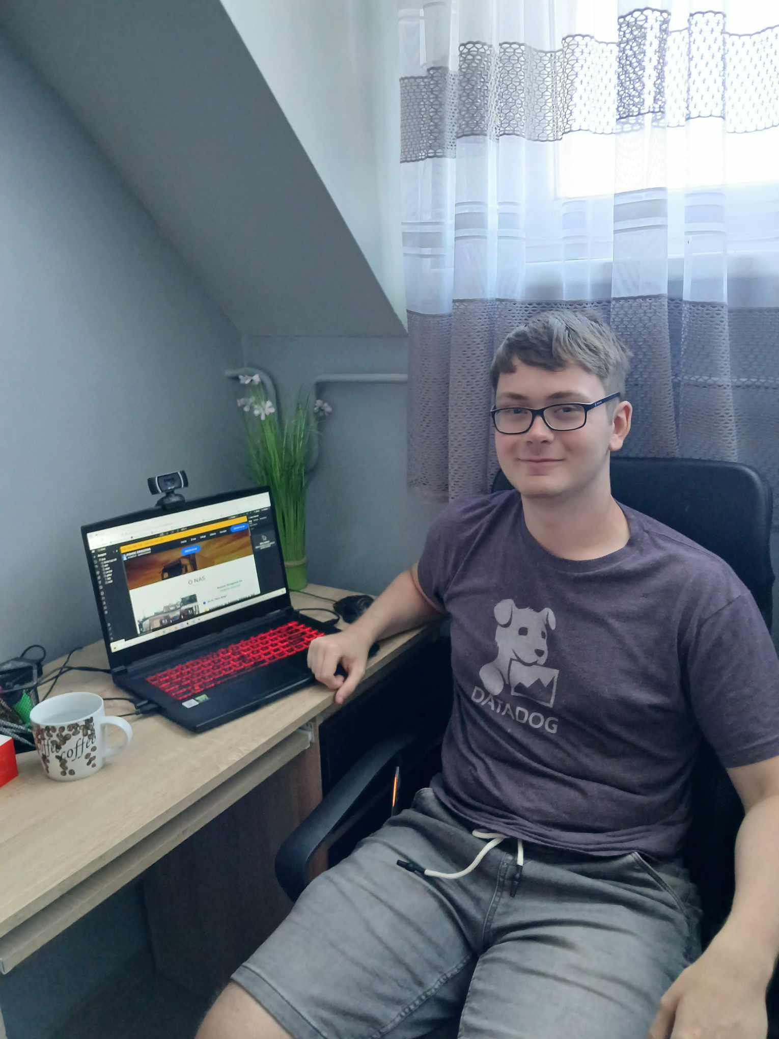 Zdjęcie twórcy strony internetowej, siedzącego przy biurku z laptopem.